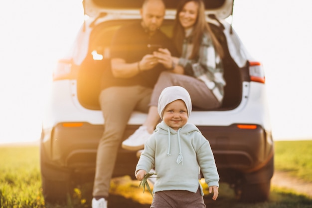 Famille arretee en bord de route pendant un long trajet en voiture avec un bebe